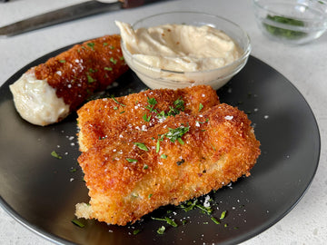 Image of golden brown croquette with creamy garlic sauce drizzled over the top
